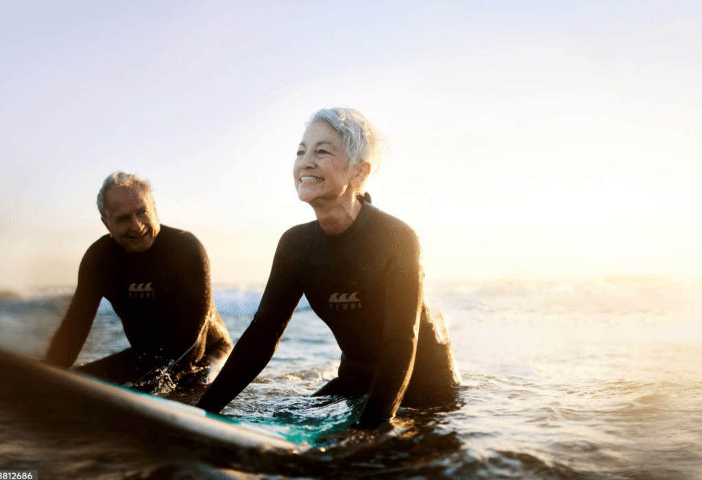 Senior couple sitting on surfboards