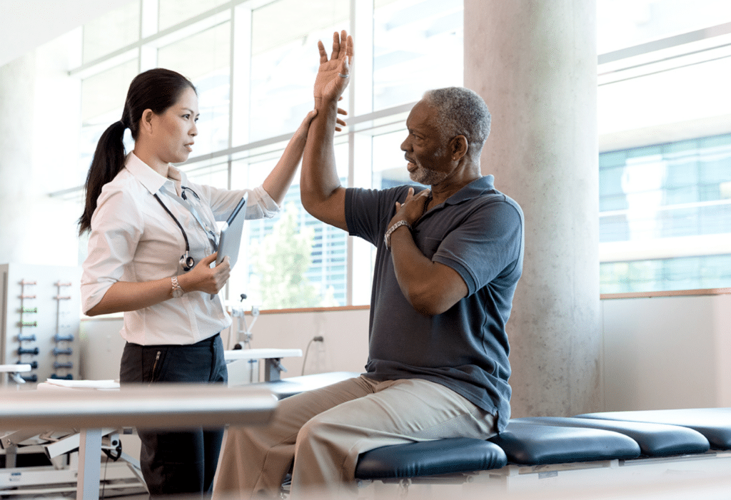 Senior man sitting on exam table talking with medical professional