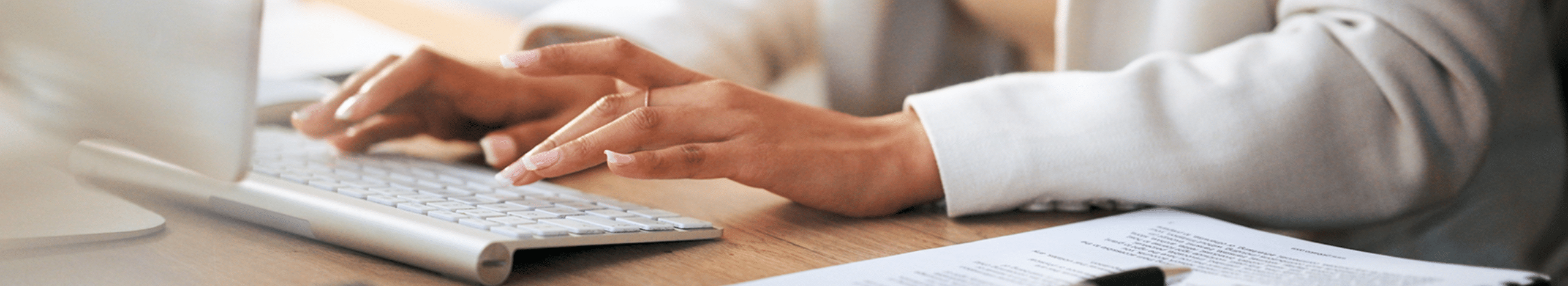 Person sitting at desk typing on computer keyboard