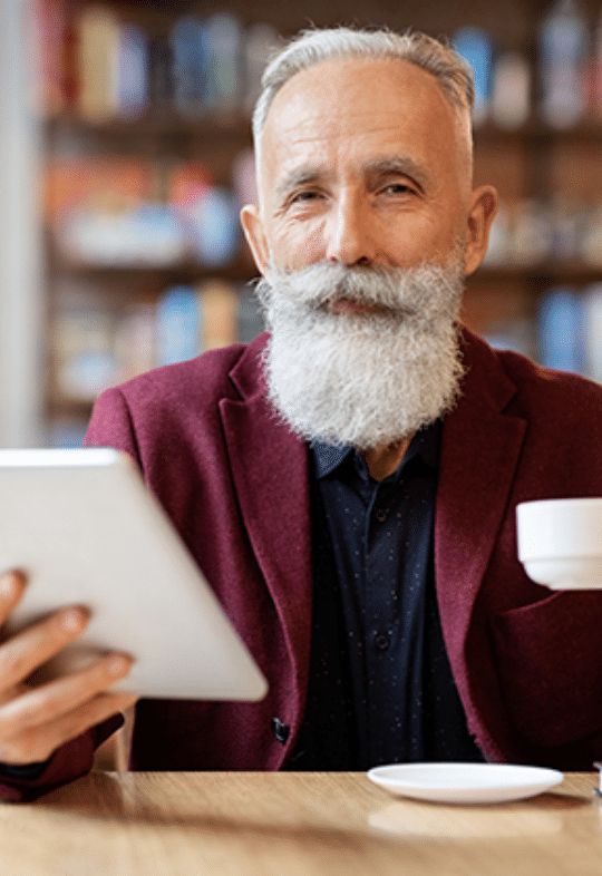 Plymouth Harbor on Sarasota Bay: Senior Man Sipping Coffee While Holding a Tablet