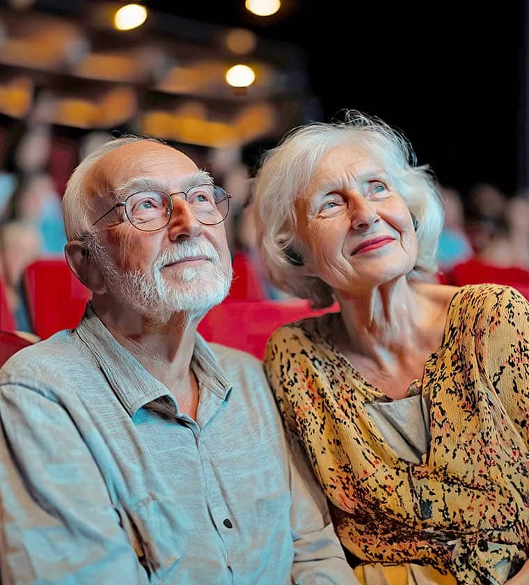 A senior couple seated in a theater