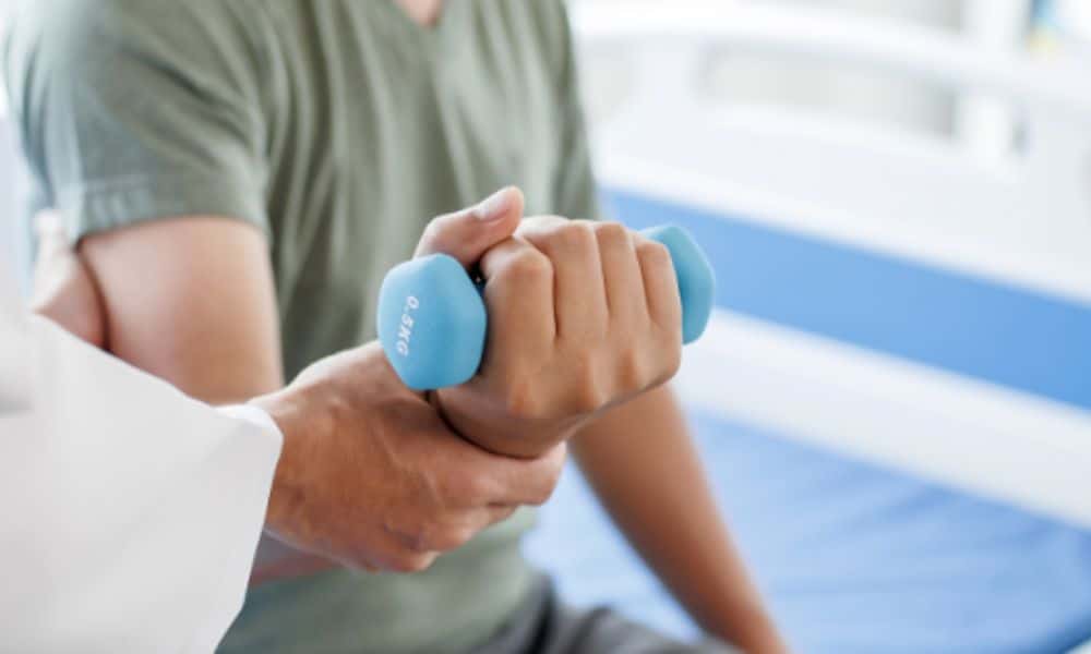 A doctor helps a person holding a blue light weight with an exercise.