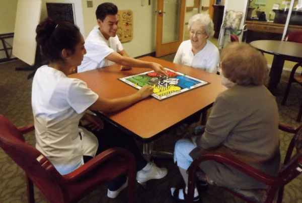 A group of four people, including two senior women and two younger individuals, playing a board game