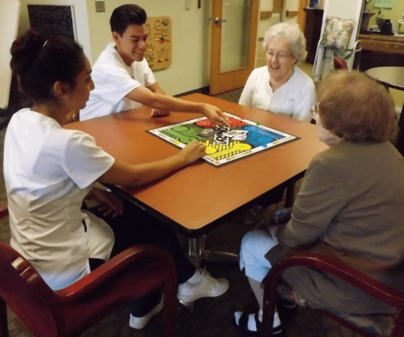 A group of four people, including two senior women and two younger individuals, playing a board game
